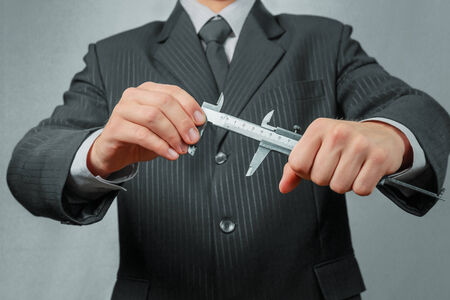 Unrecognizable businessman holds calipers, concept of business creationの写真素材