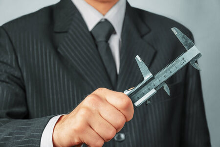 Unrecognizable businessman holds metal calipers, concept of business creationの写真素材