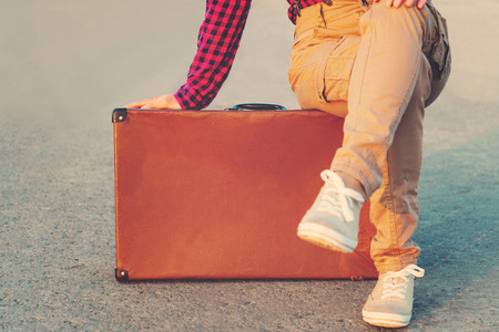 Unrecognizable woman traveler sitting on suitcaseの写真素材