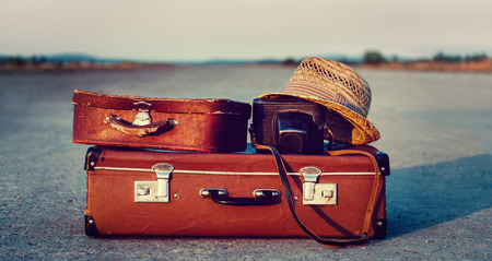 Vintage suitcases, photo camera and hat on road, concept of travel