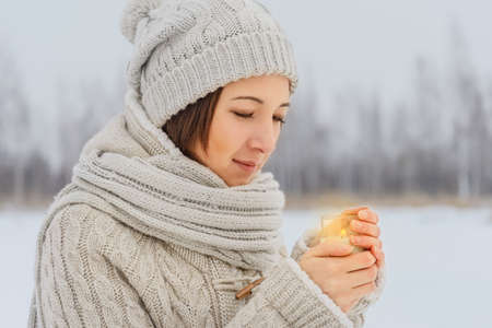Young woman holds a candle in winter weatherの写真素材