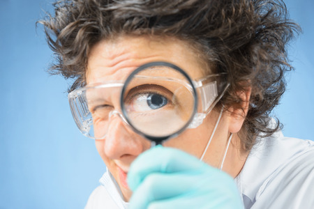 Crazy  scientist looks through a magnifying glassの写真素材
