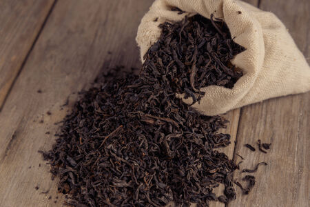 Black leaf tea in the sack on a wooden tableの写真素材