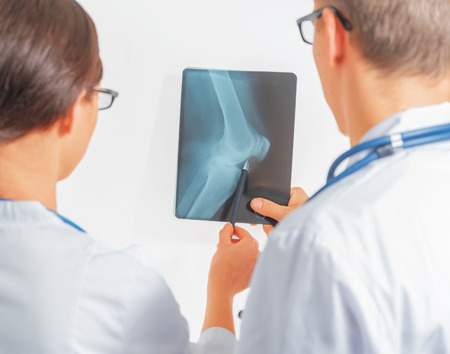 Two doctors look at x-ray picture of the knee joint, rear viewの写真素材