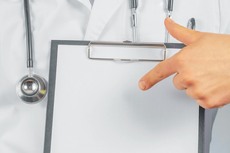 Unrecognizable man doctor is pointing on blank clipboard, space for textの写真素材