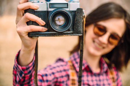 Smiling young woman with retro photo camera, focus on cameraの写真素材