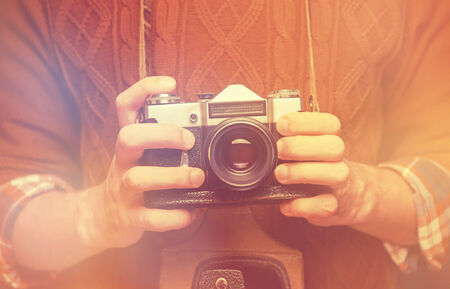 Unrecognizable man holding old retro photo camera. Image with light effectの写真素材