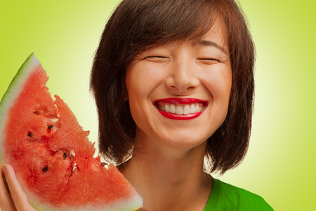 Happy young woman smiling with a piece of watermelonの写真素材