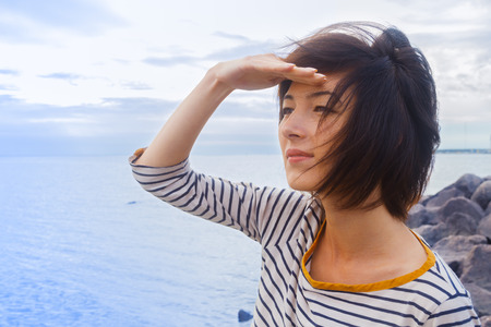 Young woman looks into the distance at seaの写真素材