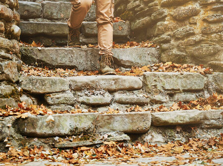 Unrecognizable woman walking down the old stone staircase in autumn outdoor, view of legsの写真素材