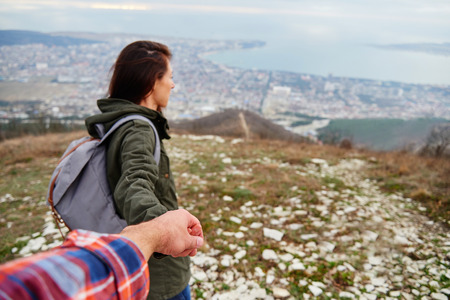Young traveler woman holding man's hand and leading him on nature outdoor. Couple in loveの写真素材