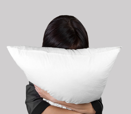 Tired female office worker rests with pillow, concept of stress workの写真素材