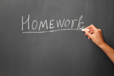 Person writes by chalk on the blackboard the word homeworkの写真素材