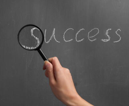 Human hand with a magnifying glass indicates on the word "success"の写真素材
