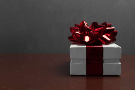Gift box with a red bow on a wooden tableの写真素材