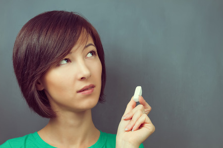 Woman holds a chalk on a background of blackboard, copyspace