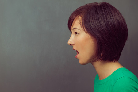 Young woman yells on the background of school board, space for text, side viewの写真素材