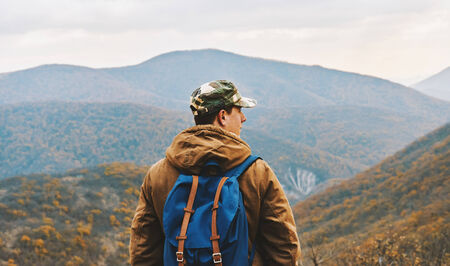 Hiker man with backpack standing among mountains and enjoying by scenics in autumn seasonの写真素材