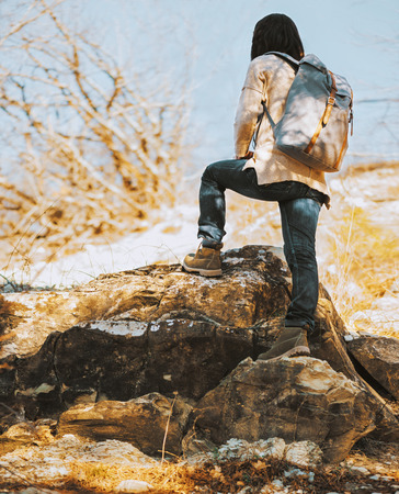 Hiker woman with backpack go up on rock, rear view. Hiking and recreation themeの写真素材