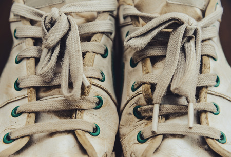 Dirty old white sneakers with shoelacesの写真素材
