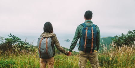 Hiker couple in love holding hands each other and enjoying view island in the seaの写真素材
