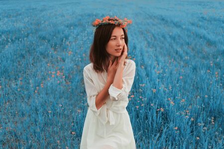 Beautiful young woman with wreath of wildflowers resting on summer meadowの写真素材