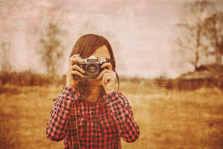 Girl takes photographs with vintage photo camera outdoor. Vintage imageの写真素材