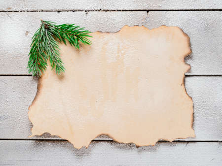 Christmas tree branch on the corner of old paper on a snowy table, copyspace