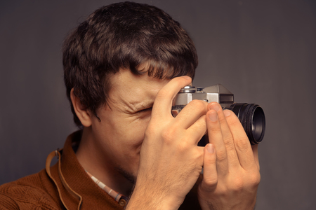 Young man looks at the old camera, space for textの写真素材