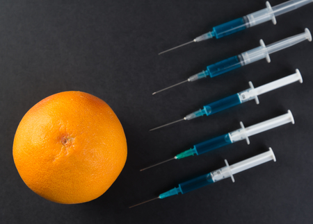 Blue liquid in the syringe and grapefruit, top viewの写真素材