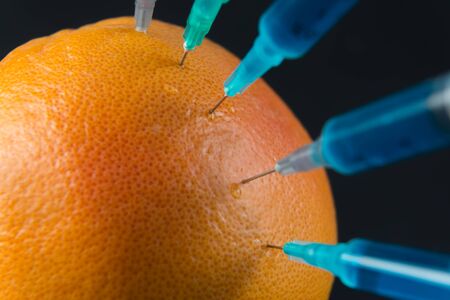 Blue liquid in the syringe injected into grapefruit, close-upの写真素材