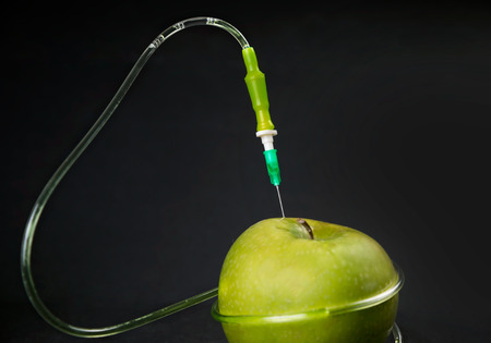 Chemical liquid in the drop counter injected into apple on a black backgroundの写真素材