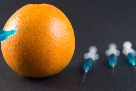 Blue liquid in the syringe injected into grapefruit, top viewの写真素材
