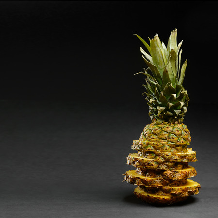Sliced ripe pineapple on a black backgroundの写真素材