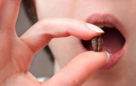 Woman holding coffee beans in mouth