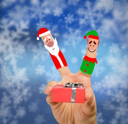 Santa and elf give a gift against a snowy の写真素材