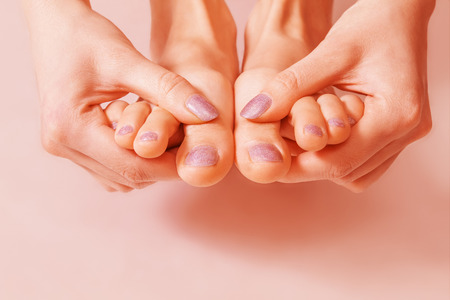 Woman shows her painted nails and toesの写真素材