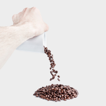 Man hand scattering a cup of coffee with grainsの写真素材