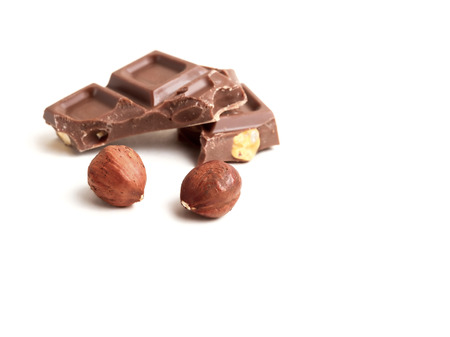 Hazelnuts and chocolate pieces on white の写真素材