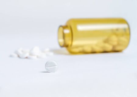Bottle with a handful of pillsの写真素材