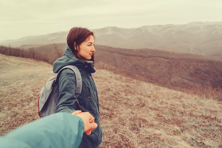 Hiker woman holding man's hand on nature in the mountains. Couple in love. Focus on woman. Point of...