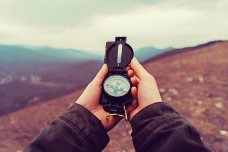 Hiker woman searching direction with a compass in the mountains. Point of view shotの写真素材