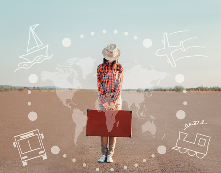 Traveler young woman standing with a suitcase on road. Map of the world and types of transport on image. Concept of travelの写真素材