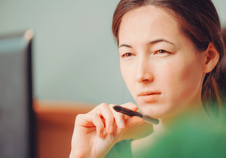 Pensive young woman working over laptop in the officeの写真素材