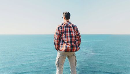 Young man enjoying view of sea in summer, rear viewの写真素材