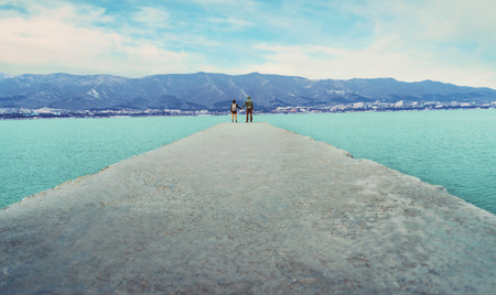 Couple in love standing on pier at bay and enjoying view of mountain