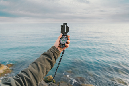 Traveler searching direction with a compass on coast near the sea in summer. Point of viewの写真素材