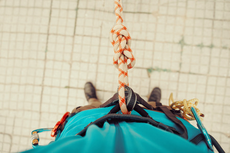 Climber man standing in harness with rope and knot Eight. Point of view shot. Top viewの写真素材