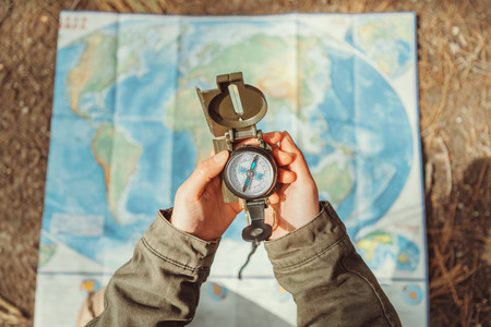 Traveler woman searching direction with a compass on background of map outdoor. Close-up. Point of view shotの写真素材