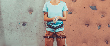 Climber young woman coating her hands in powder chalk magnesium and preparing to climb indoorの写真素材